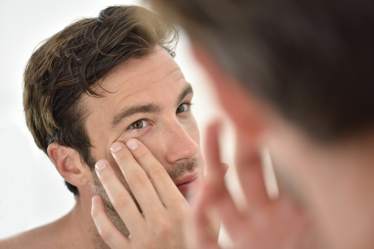 Handsome man applying facial cream in front of mirror Handsome man applying facial cream in front of mirror